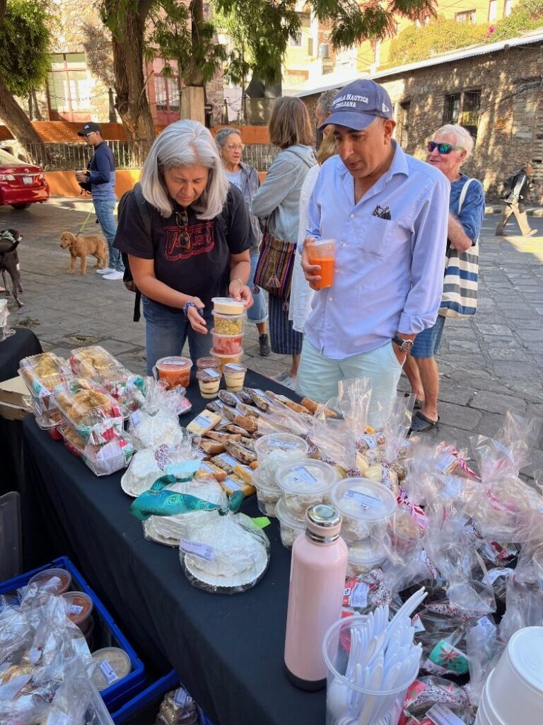 A group of people standing next to a table with food Description automatically generated