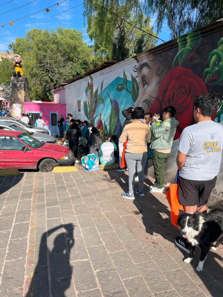 A group of people standing next to a wall with a mural on the side Description automatically generated