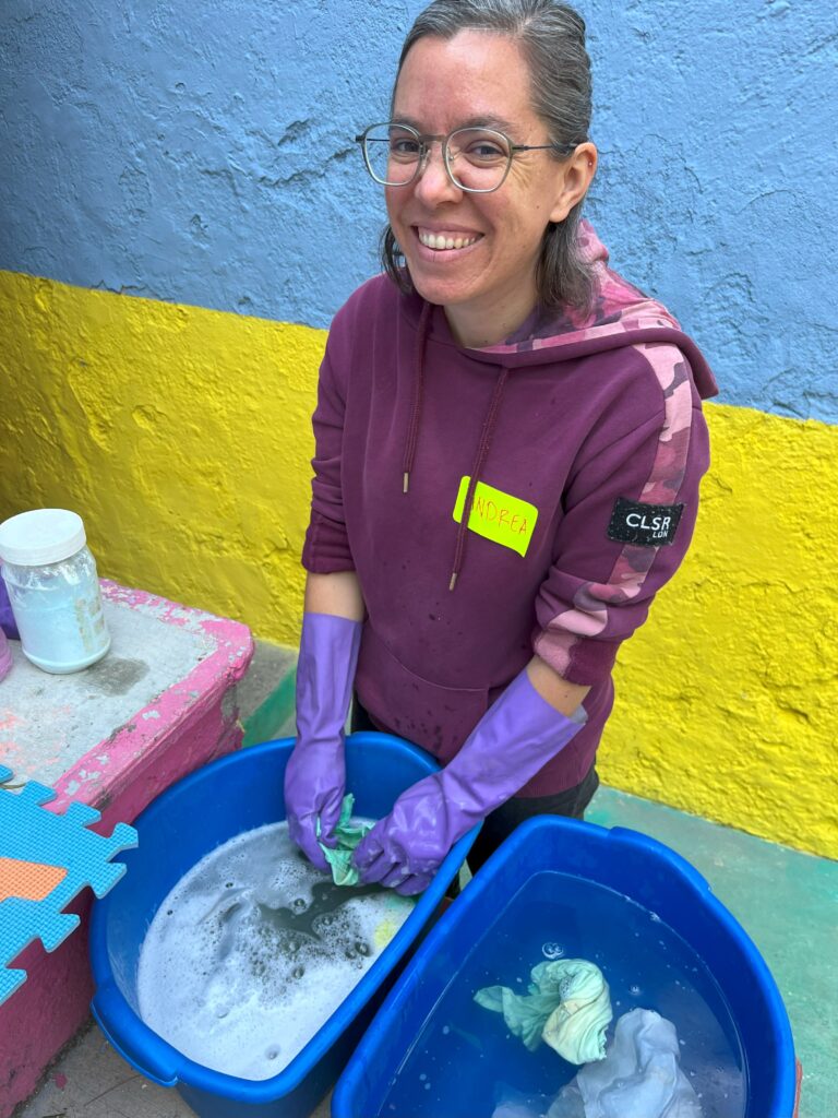 A person wearing glasses and gloves washing a bucket of water Description automatically generated